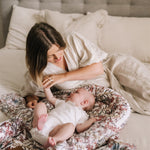 Woman playing with a baby on a floral baby nest or baby lounger in a bedroom setting