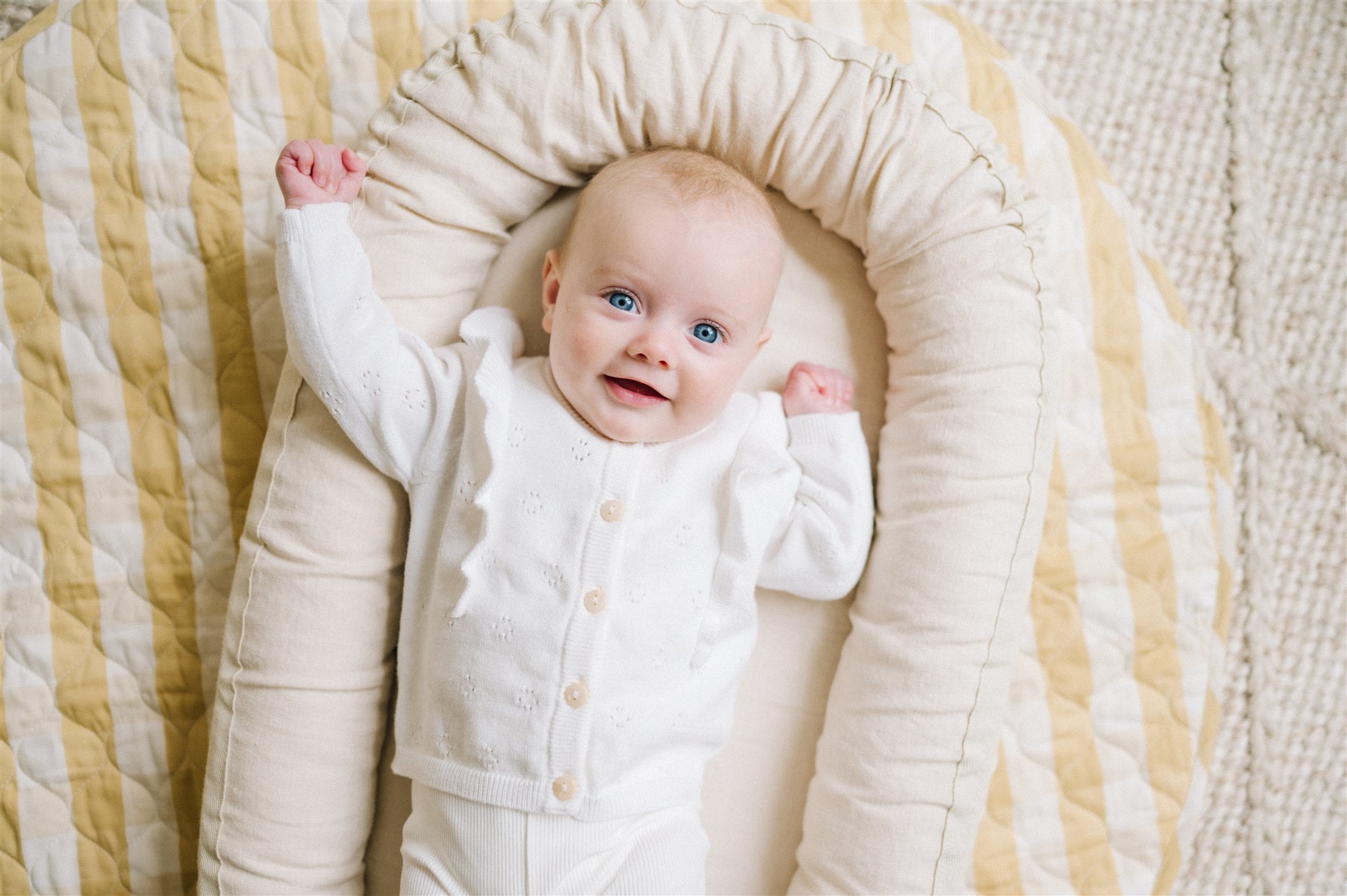 Happy baby in natural baby nest on top of organic playmat 